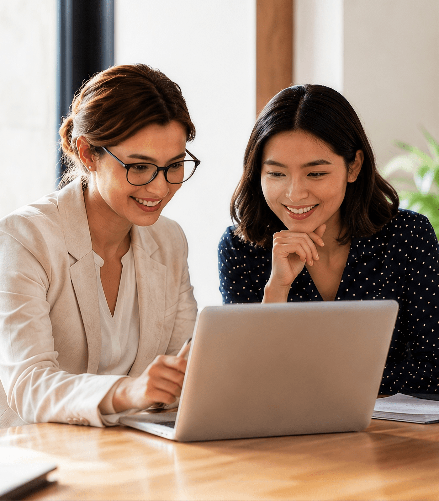 Two colleagues smiling while reviewing something together on a laptop